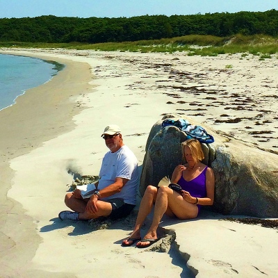 Two people sit on a beach